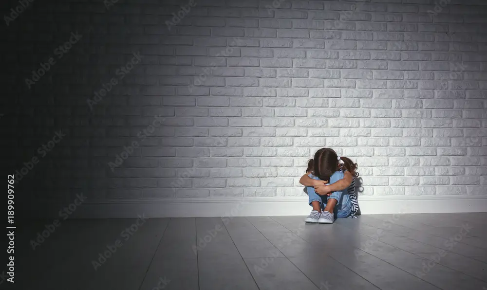 upset sad sad child girl in stress cries at an empty dark wall